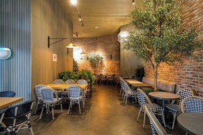 A restaurant with a brick wall, wooden ceiling, and patterned chairs. Tables are arranged for dining. - 2BR Uptown Condo BGC-22Floor view and near Mitsukoshi & Uptown Mall, Restaurants (Makati City)