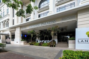 The entrance of Uptown Palazzo hotel with a sign, steps, and surrounding greenery. - 2BR Uptown Condo BGC-22Floor view and near Mitsukoshi & Uptown Mall, Restaurants (Makati City)