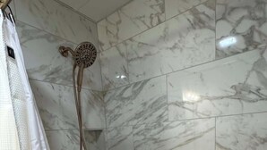 A bathroom with a bathtub, a shower with a handheld showerhead, and a curtain.