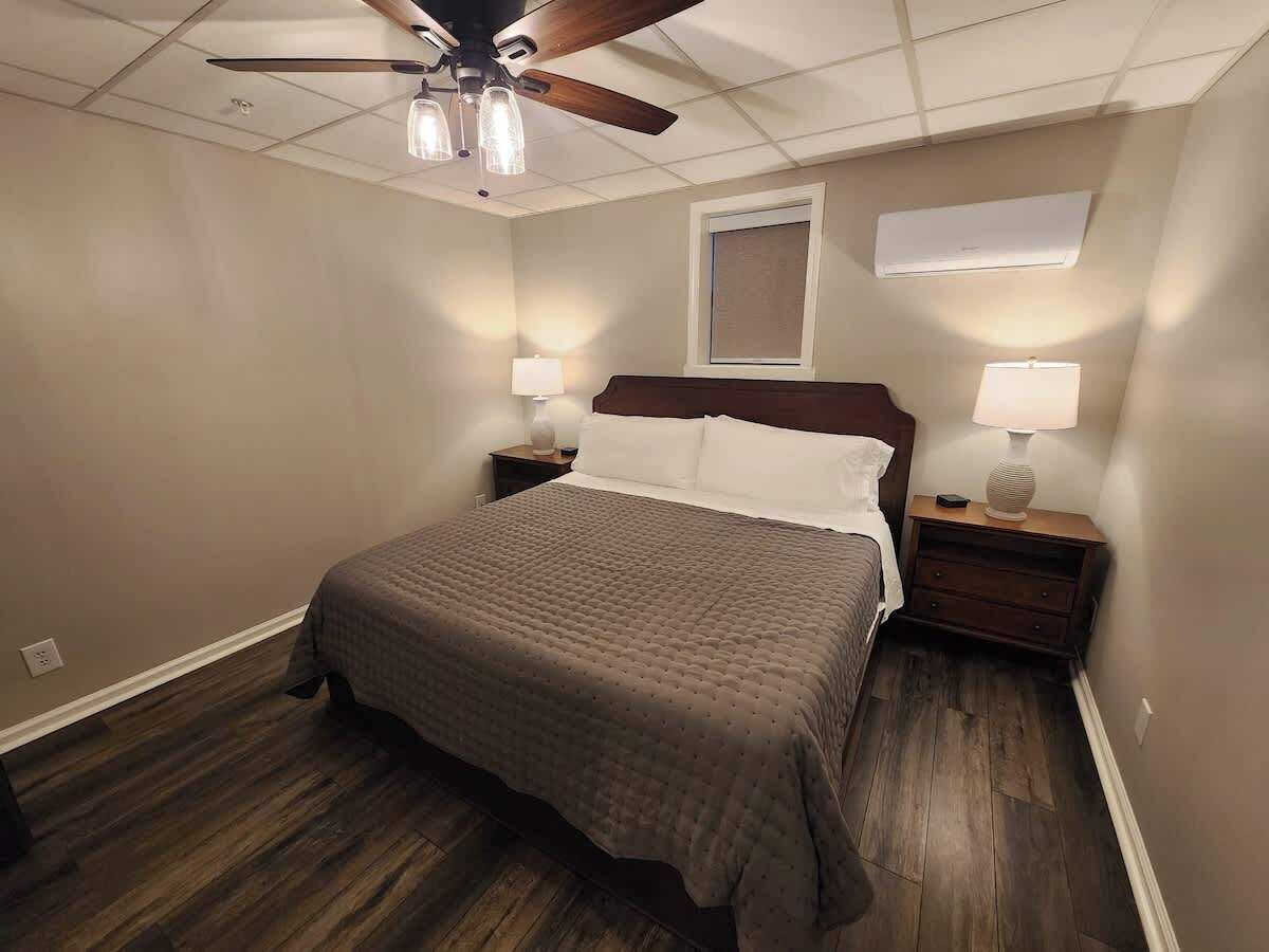 Een slaapkamer met een bed, nachtkastjes, een plafondventilator en een airconditioning.