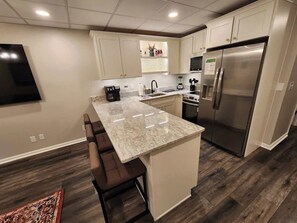 Eine moderne Küche mit einer zentralen Kochinsel, Edelstahlgeräten und einem Barhocker.