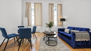Ein modernes Wohnzimmer mit einem blauen Sofa, passenden Sesseln, einem runden Couchtisch und einer Stehlampe.
