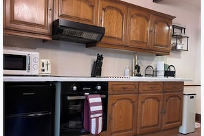 A kitchen with wooden cabinets, a microwave, a toaster, and a stove.