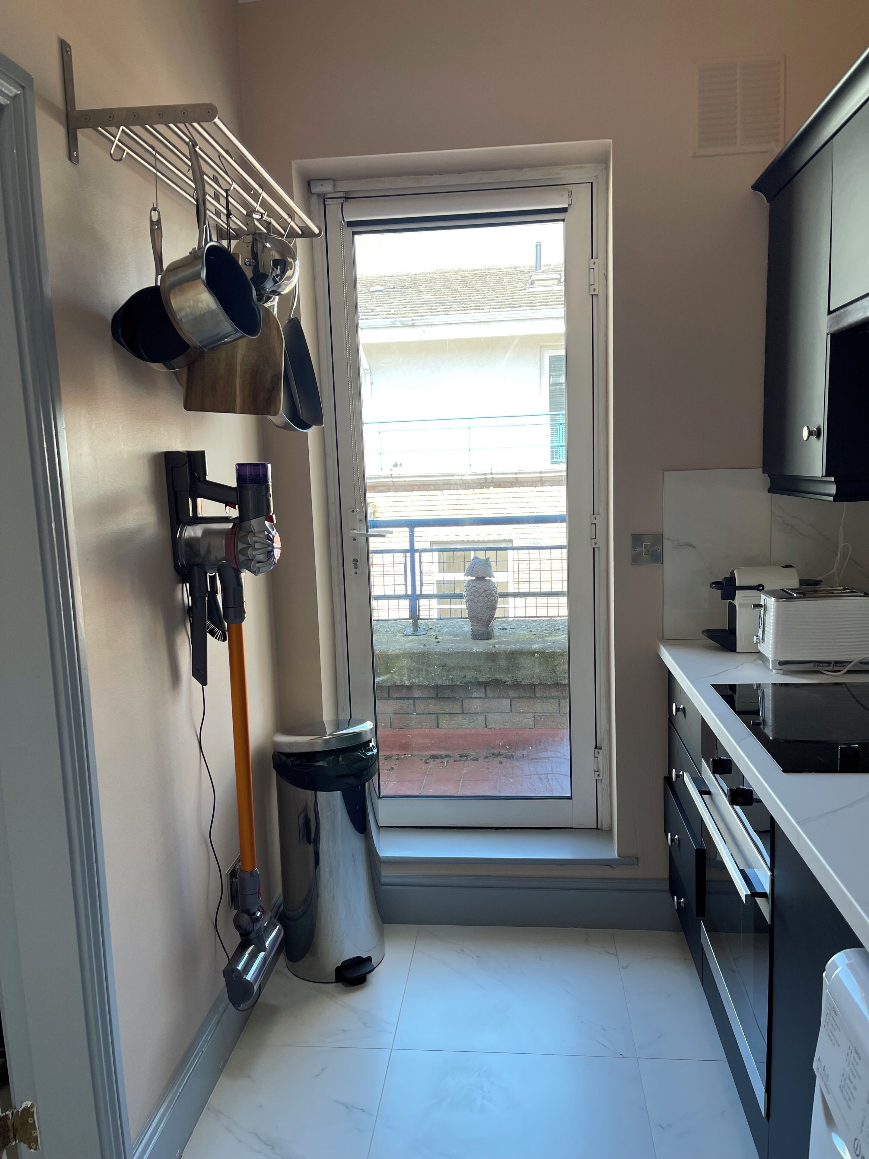A kitchen with a window, a trash bin, and a microwave.
