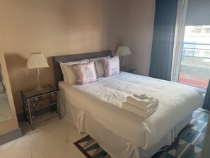 A hotel room with a bed, two bedside lamps, a glass table, a window with a view, and a patterned rug. - Apartment 54, Castle Gate is a spacious top-floor apartment in the heart of Dub (Dublin)