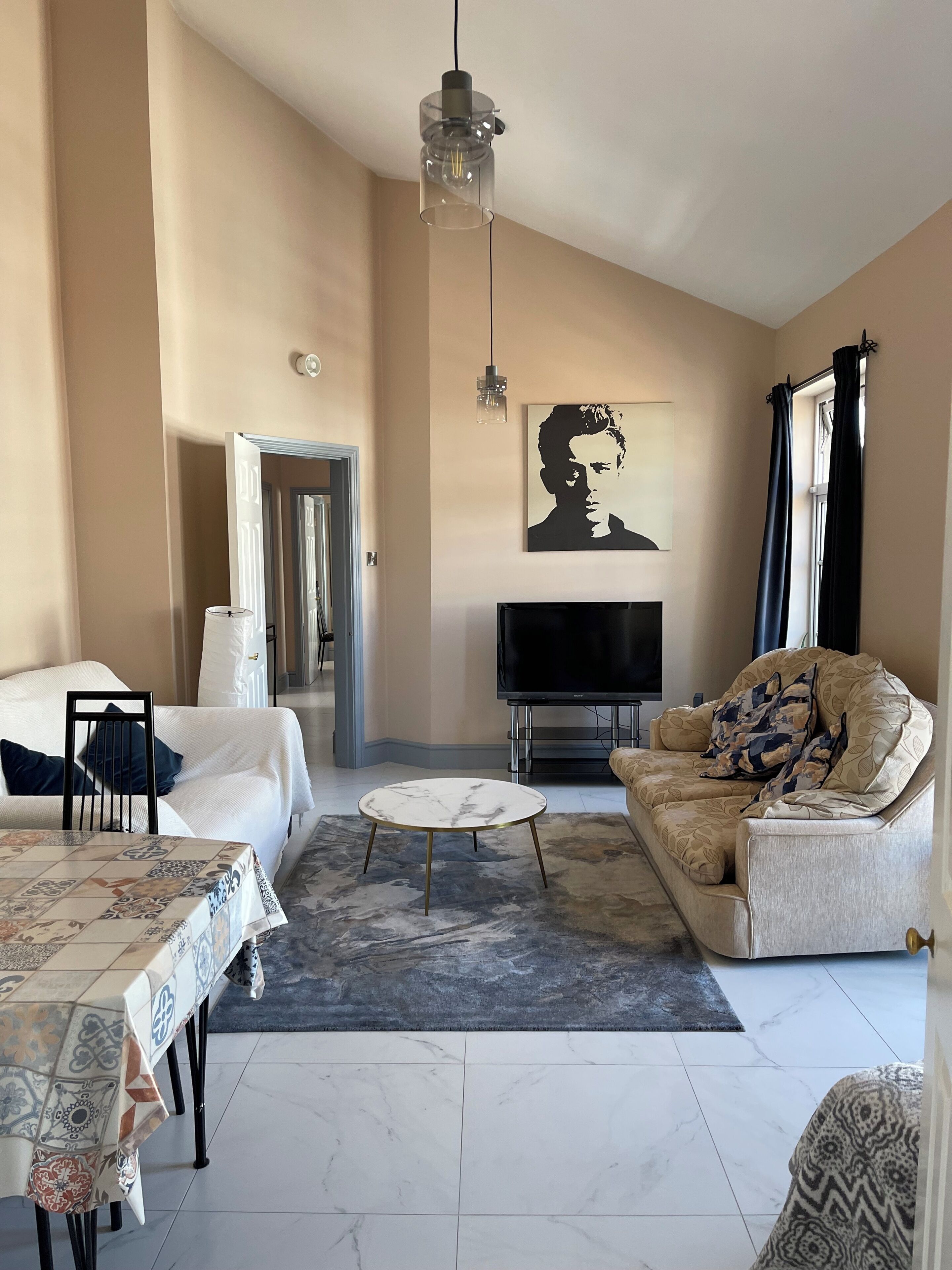 A modern living room with a sofa, a coffee table, a TV, and a painting on the wall.