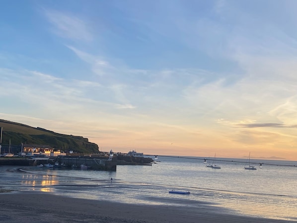 A coastal scene with boats, a pier, and buildings along the shore.