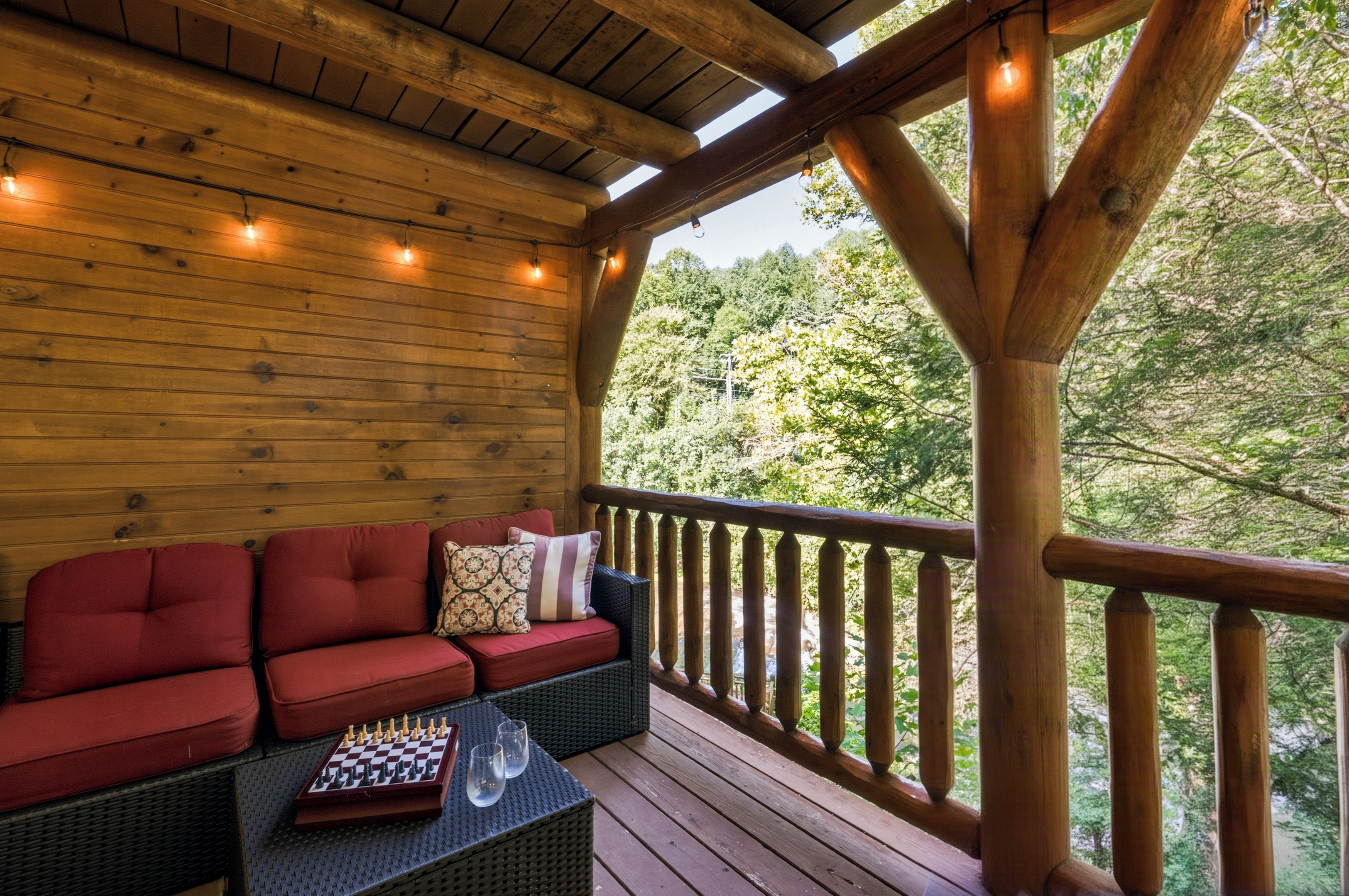 A wooden deck with a red sofa and a chessboard.