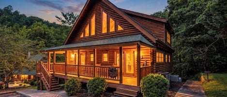 A log cabin with a porch, a staircase, and a front door.