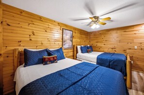 A cabin-style room with two beds, wooden walls, a ceiling fan, and a framed picture on the wall. - Relax by the Waterfall ,Hot Tub,Pet-Friendly (Sevierville)