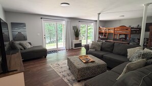 A modern living room with a sofa, ottoman, and a television.