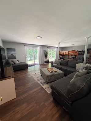A modern living room with a sofa, ottoman, and a television.