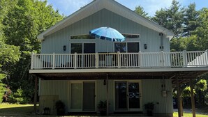 A two-story house with a balcony, a covered porch, and a large umbrella.