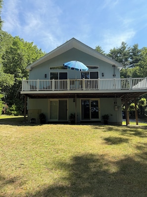 A two-story house with a balcony, a covered porch, and a large umbrella.