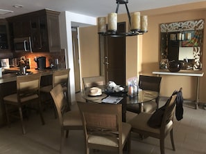 A dining area with a round glass table, four chairs, and a chandelier.