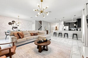 Una sala de estar moderna con un sofá, una mesa de centro y un mural de Mickey Mouse en la pared.