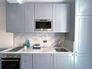 A modern kitchen with grey cabinets, a built-in oven, and a marble countertop. - Serene 1-bedroom apartment with AC in Il-Belt Valletta (Il-Belt Valletta)