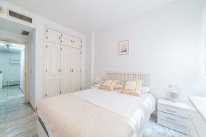 A bedroom with a bed, bedside tables, a wardrobe, and a door leading to another room. - Home2Book Sevilla Terrace & Pool Apt (Seville)