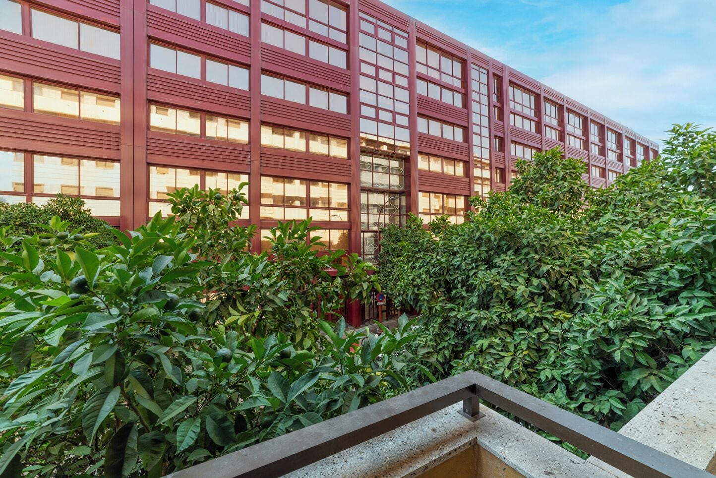 Een modern gebouw met een rode gevel en meerdere ramen.