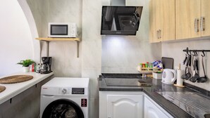 Uma cozinha compacta com máquina de lavar, micro-ondas e fogão.