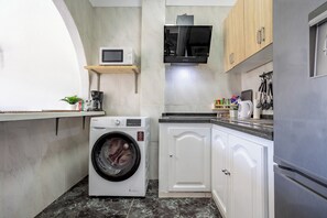 A compact kitchen with a washing machine, microwave, and a coffee machine. - Home2Book Ocean & Mountain View in San Andrés (San Andres de Tenerife)