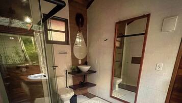 Casa de banho moderna com cabine de duche em vidro, lavatório branco e espelho grande.