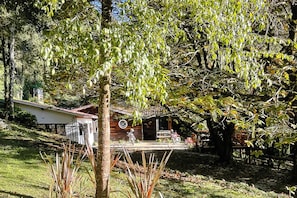 Una casa con un porche, un jardín pequeño y un árbol en primer plano.