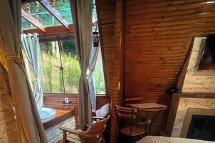 A wooden interior with a fireplace, a dining table, and a window with curtains.