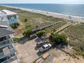 Ein Küsteneigentum mit Strandblick, einem Parkplatz und einem Gebäude mit Balkonen.