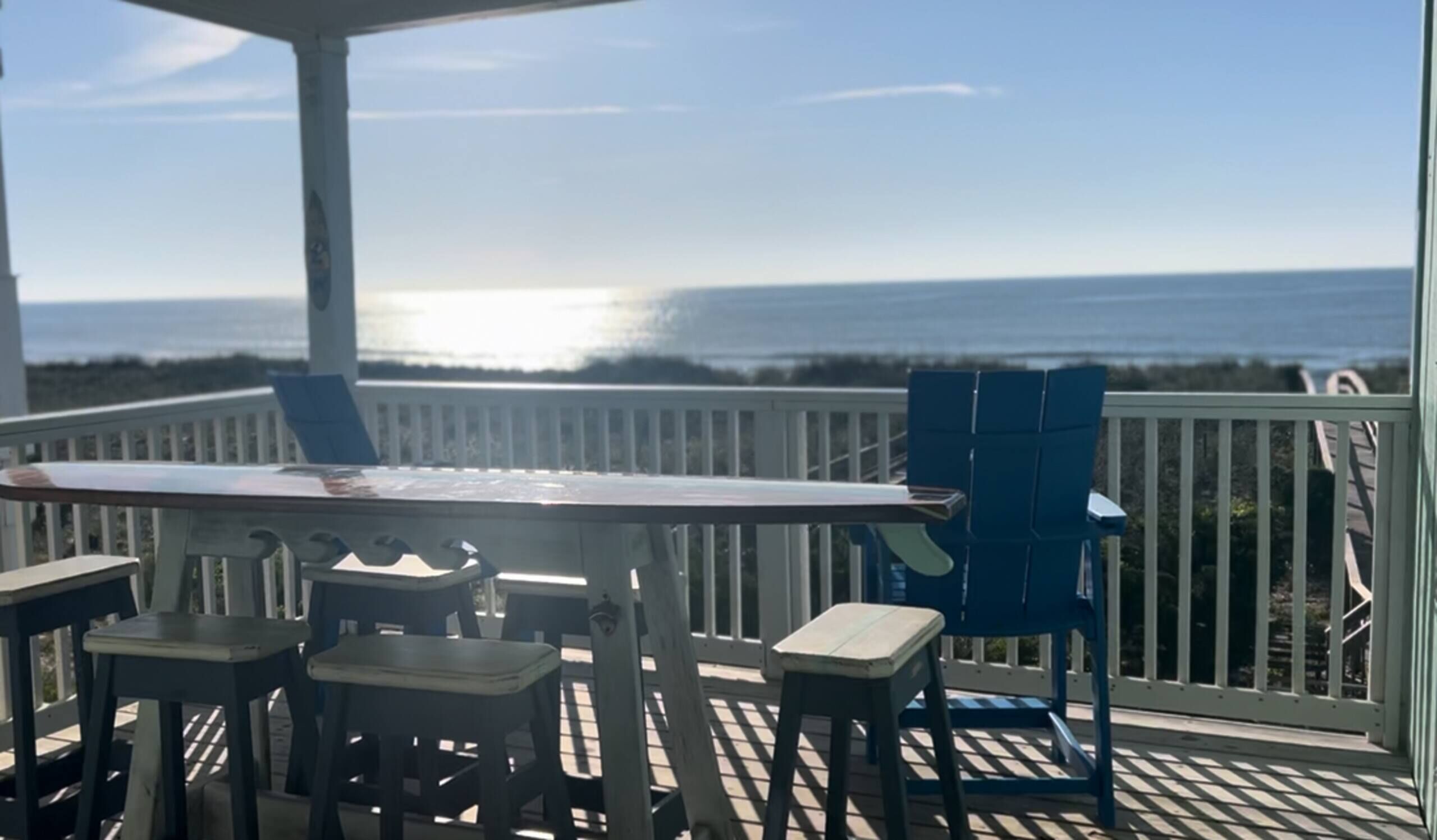 A deck with a table and chairs, overlooking a body of water.