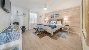 Una camera da letto con un letto, comodini, una ventola a soffitto e una parete in legno.