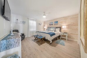 A bedroom with a bed, bedside tables, a ceiling fan, and a wooden wall. - Luxury Oceanfront Carolina Beach Condo w/ Private Beach Access. Full ocean view! (Carolina Beach)