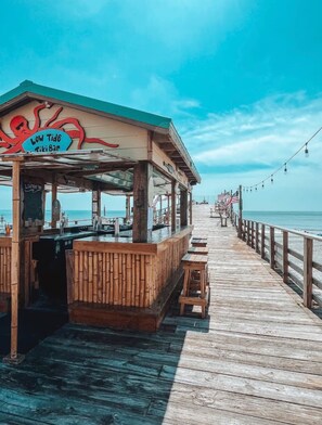 Eine hölzerne Steg, der zu einer Tiki-Bar führt, mit einem Schild, auf dem 'Low Tide Tiki Bar' steht.