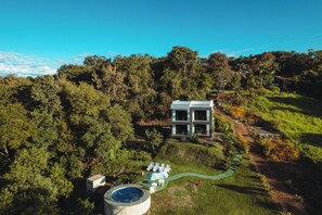 Un edificio moderno con piscina, rodeado de un bosque denso.