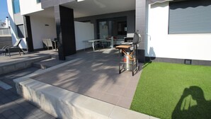 A modern outdoor patio with a dining area, a grill, and a small garden. - Groundfloor Oasis Beach VII Punta Prima (Torrevieja)