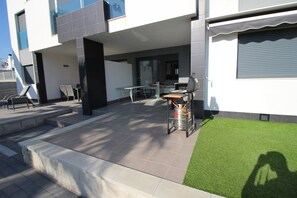 Eine moderne Außenpatio mit Essbereich, Grill und kleinem Garten.