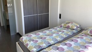 A bedroom with a bed, a wardrobe, and a small bedside table. - Groundfloor Oasis Beach VII Punta Prima (Torrevieja)