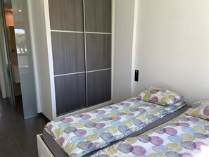 Ein Schlafzimmer mit Bett, Kleiderschrank und einem kleinen Nachttisch.