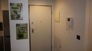 A hotel room with a closed door, a wall-mounted phone, and two beverage posters. - Groundfloor Oasis Beach VII Punta Prima (Torrevieja)