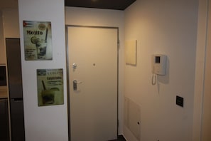Ein Hotelzimmer mit geschlossener Tür, einem an der Wand befestigten Telefon und zwei Werbeplakaten für Getränke.