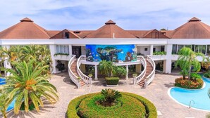 Un resort con un patio central, piscina y un mural de una tortuga marina.