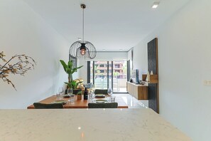 A modern dining area with a marble table, chairs, a hanging light fixture, and a view of the outside. - Groundfloor Villamartin Amanecer (Orihuela)