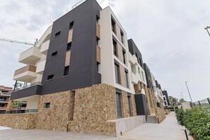 A modern multi-story building with balconies, a stone facade, and a clear sky. - Groundfloor Villamartin Amanecer (Orihuela)