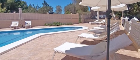 A poolside area with lounge chairs and umbrellas.