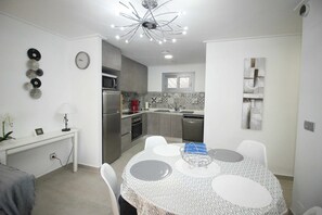 A modern kitchen with grey cabinets, a stainless steel refrigerator, and a tiled backsplash. - Groundfloor Property Amalia Torrevieja (Torrevieja)