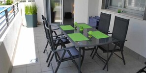 A dining area with a glass table, black chairs, and green placemats. - Groundfloor Property Amalia Torrevieja (Torrevieja)
