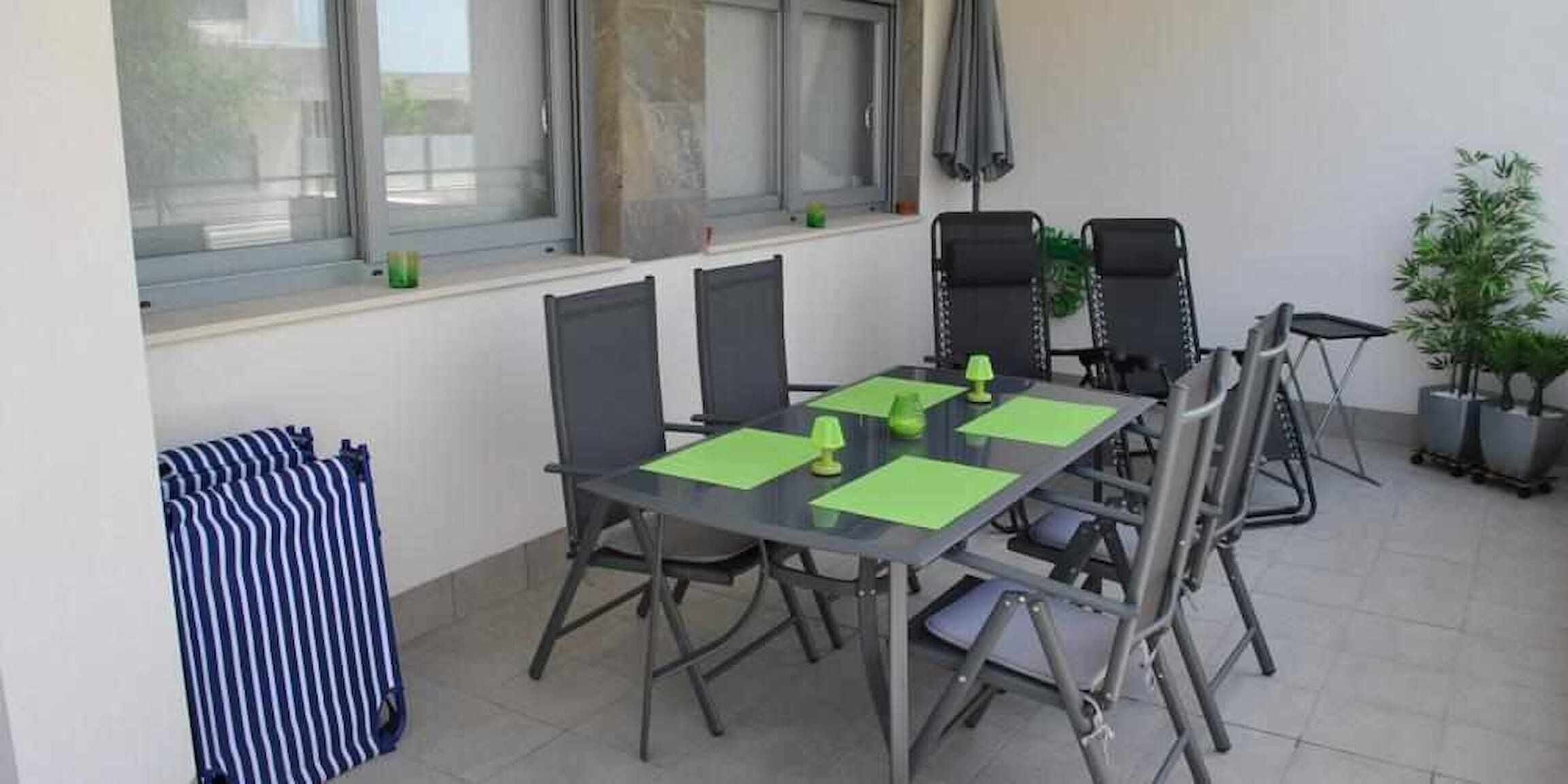 Ein Essbereich mit Tisch und Stühlen, einem Fenster mit Jalousien und einer Zimmerpflanze.