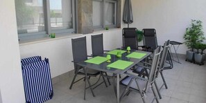A dining area with a table and chairs, a window with blinds, and a potted plant. - Groundfloor Property Amalia Torrevieja (Torrevieja)