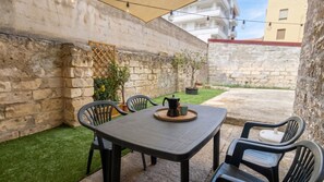 Eine Terrasse mit Tisch, Stühlen, einer Kaffeekanne und einer Tasse.