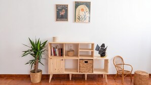 A wooden shelf with books, a potted plant, and a wicker basket. - Chez Mich - Two Bedroom Apartment, Sleeps 5 (Alghero)